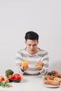 Man having hard choice between healthy and unhealthy food