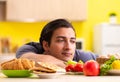 Man having hard choice between healthy and unhealthy food Royalty Free Stock Photo