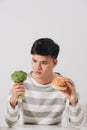 Man having hard choice between healthy and unhealthy food Royalty Free Stock Photo