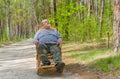 Man is having rest in forest sitting on a wicker rocking-chair Royalty Free Stock Photo