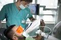 Man having teeth whitening by dental UV whitening device,dental assistant taking care of patient.Eyes protected with glasses Royalty Free Stock Photo