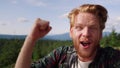 Man having video chat at hike in mountains. Male hiker celebrating victory