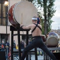 Man with Headband Playing Vertical Drum of Japanese Musical Tradition during a Public Outdoor Event