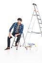 man in headband sitting on ladder with paint roller Royalty Free Stock Photo