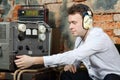 Man in headphones configures power source to radio receiver