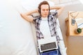 Man in headphones lying down on the couch at home and enjoying listening music