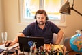 Man with headphones and microphone having conference call online sitting at home office with two laptops.