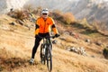 Man in helmet and glasses stay on the bicycle under landscape with rocks and hill.