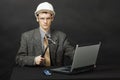 Man in helmet with hammer repairs computer Royalty Free Stock Photo