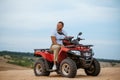 Man with helmet in hand poses on atv in desert Royalty Free Stock Photo