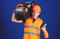 Man in helmet, hard hat carries toolbox and holds hammer, blue background. Worker, repairer, repairman, builder on calm