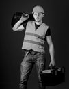 Man in helmet, hard hat holds toolbox and suitcase with tools, blue background. Equipped repairman concept. Worker Royalty Free Stock Photo