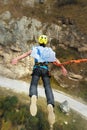 A man in a helmet jumps ropeup with an empty flag in the mountains. Extreme sports. Leisure. Top view