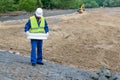 A man in a helmet looks at a road construction plan at an object Royalty Free Stock Photo