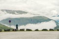 Man in helmet photographer taking photos back view of mountains landscape in rainy weather in Norway. Travel Lifestyle Royalty Free Stock Photo