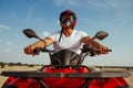 Man in helmet poses on atv in desert, front view Royalty Free Stock Photo