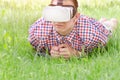 Man in a helmet of virtual reality lies on a green grass Royalty Free Stock Photo