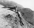 Man helping another man from falling down a cliff