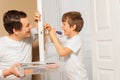 Man helping his son to draw up bolt of door handle Royalty Free Stock Photo