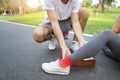 Man helping jogger woman who hurt the ankle from too much exercise in the park Royalty Free Stock Photo