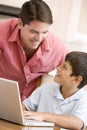 Man helping young boy in kitchen with laptop Royalty Free Stock Photo