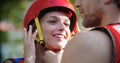 Man helps woman to wear sport helmet and life jacket before whitewater rafting descent. People wearing life vests