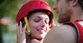Man helps woman to wear sport helmet and life jacket before whitewater rafting descent. People wearing life vests