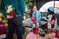 Man hide red gift box backside for surprise girlfriend, who sit on sofa with friend