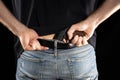 Man hides a gun behind a trouser belt on a black background