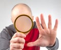 man hides his face with a magnifying glass. The concept of searching for a person in a database. Look at the world incognito.