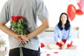 Man hiding beautiful red rose bouquet behind back, ready to give Valentine flower present to lover girlfriend for celebration, Royalty Free Stock Photo