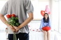 Man hiding beautiful red rose bouquet behind back, ready to give Valentine flower present to lover girlfriend for celebration, Royalty Free Stock Photo