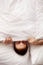 Man hiding in bed under sheets. Royalty Free Stock Photo