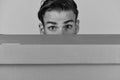 Man hiding behind cardboard box on grey background