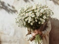Man hiding behind a large bouquet of wild daisy flowers, against a sunlit wall. Flowers from the garden. Generative AI Royalty Free Stock Photo