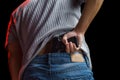 Man hiding his gun in his jeans on black background