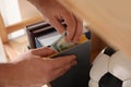 Man hiding money in book indoors. Financial savings