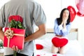 Man hiding red gift box with beautiful red rose bouquet behind back, ready to give Valentine present to lover girlfriend for Royalty Free Stock Photo