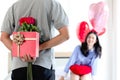 Man hiding red gift box with beautiful red rose bouquet behind back, ready to give Valentine present to lover girlfriend for Royalty Free Stock Photo