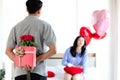 Man hiding red gift box with beautiful red rose bouquet behind back, ready to give Valentine present to lover girlfriend for Royalty Free Stock Photo