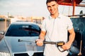 Man with high pressure washer on car wash station