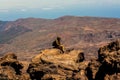 Man hiker with backpack enjoying view of Teide caldera. Tourist sitting on rocks on the volcano against the backdrop of incredible