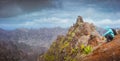 Man hiker with backpack sitting on the mountain top and looking down to the valley. Stunning arid landscape on Santo Royalty Free Stock Photo