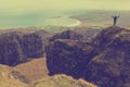 Man hiker with backpack standing on rock cliff with hands spread