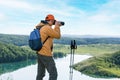 Man hiker with backpacks relaxing and taking photos during trek on top of the mountain