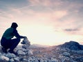 Man hiker is building pebbles pyramid. Stones on Alps mountain summit. Daybreak horizon Royalty Free Stock Photo