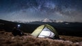 Male tourist have a rest in his camping in the mountains at night under beautiful night sky full of stars and milky way Royalty Free Stock Photo