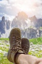 Man hiker lie on a ground. Peaks like a background. Sunny day.Trekking boots.Lens flare. Succesful backpacker enjoy a view. Royalty Free Stock Photo