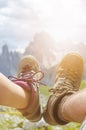 Man hiker lie on a ground. Peaks like a background. Sunny day.Trekking boots.Lens flare. Succesful backpacker enjoy a view. Royalty Free Stock Photo