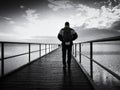 Man hiker on mole at sea. Tourist on wharf looking ower sea to horizon